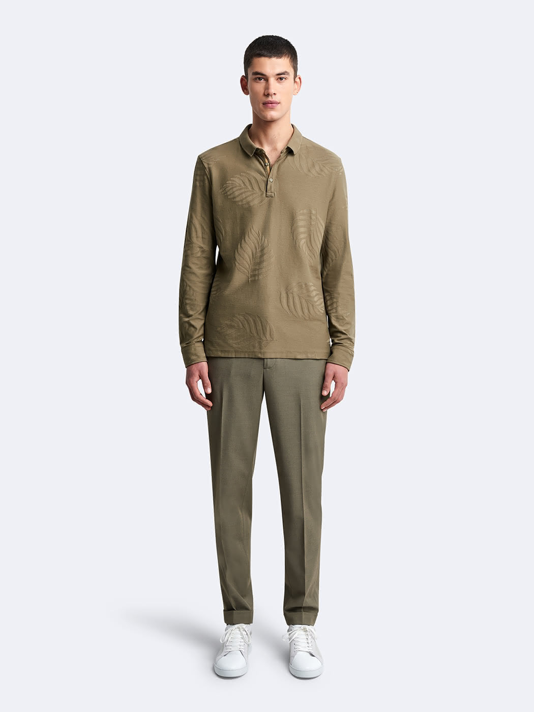 Vue en pied du mannequin portant le polo Devred kaki à manches longues avec détails feuilles adapté par Adapt & Joy, conçu pour allier confort, élégance et facilité d’habillage pour les personnes en situation de handicap ou seniors