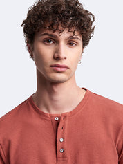 Portrait d’un mannequin portant le t-shirt Devred orange à manches longues et col tunisien Devred adapté par Adapt & Joy, conçu pour faciliter l’habillage tout en conservant élégance et confort pour les personnes en situation de handicap ou seniors