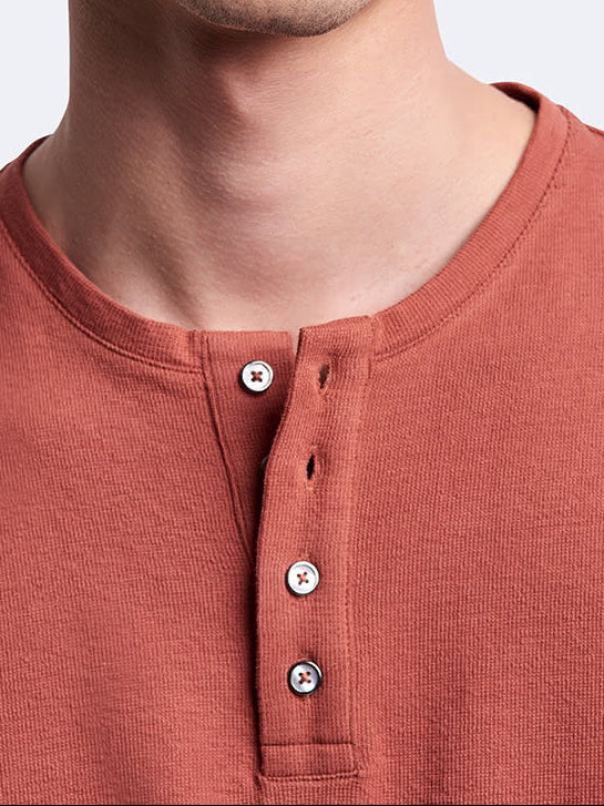 Portrait d’un mannequin portant le t-shirt Devred orange à manches longues et col tunisien Devred adapté par Adapt & Joy, conçu pour faciliter l’habillage tout en conservant élégance et confort pour les personnes en situation de handicap ou seniors