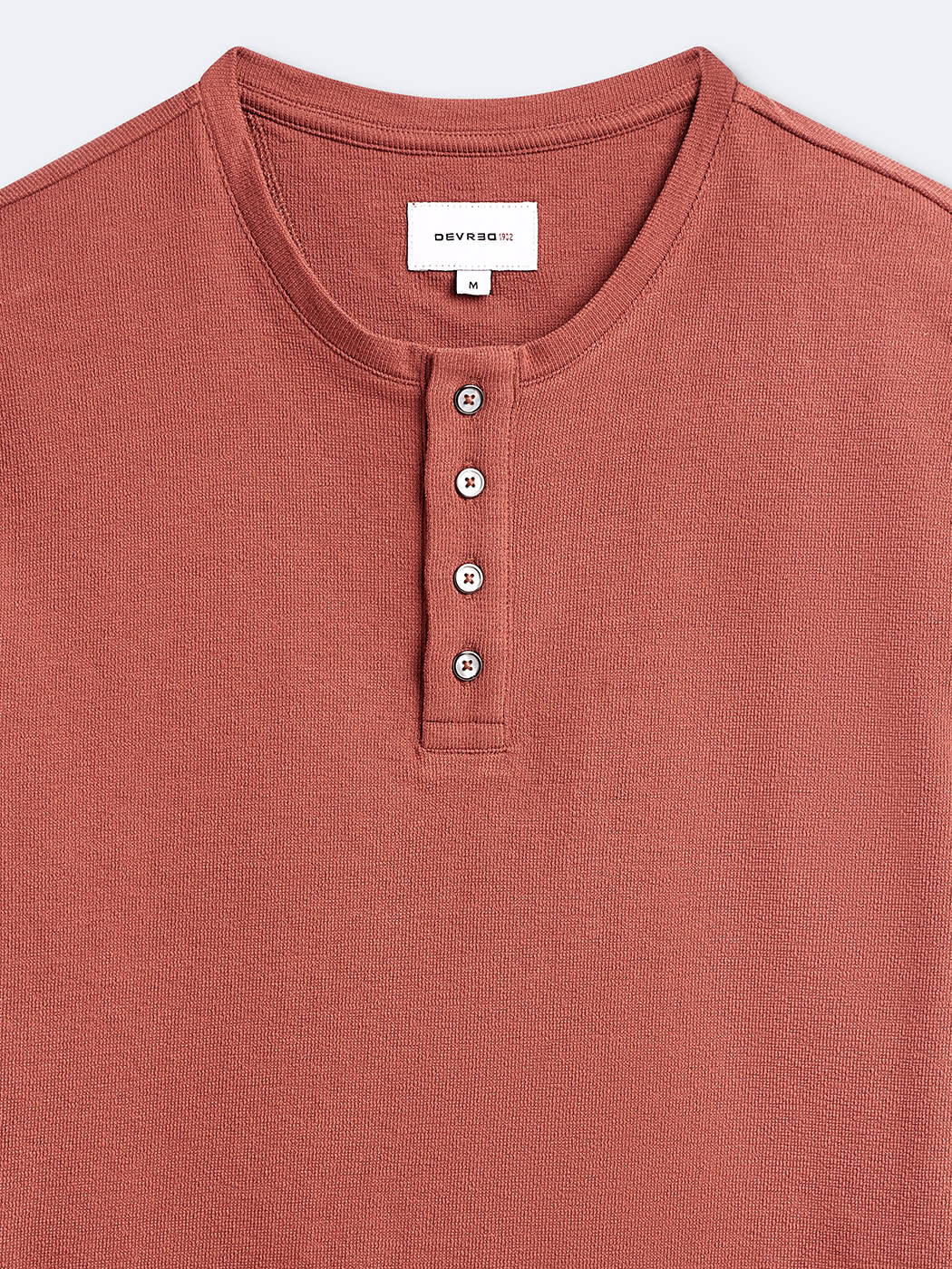 Zoom sur le t-shirt orange à manches longues et col tunisien Devred adapté par Adapt & Joy, avec ouverture facilitée pour l’habillage des personnes en situation de handicap ou seniors